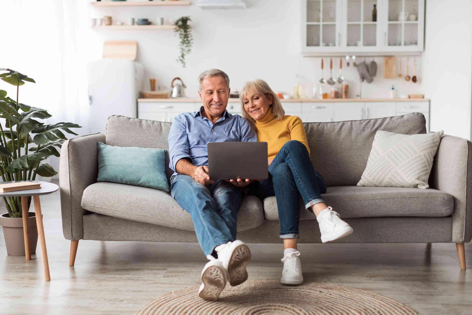 Ein älteres Ehepaar auf einer Couch mit einem Laptop