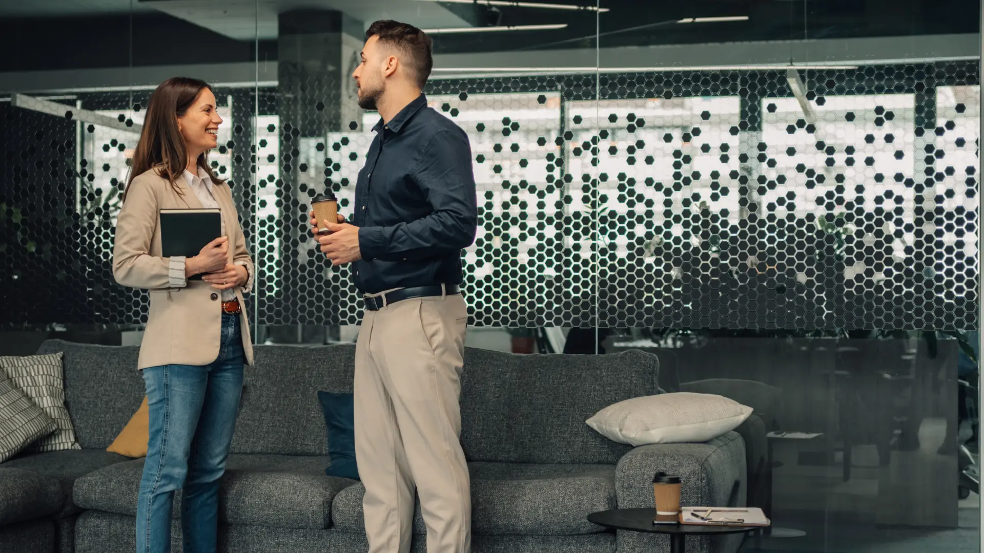 Zwei Support-Mitarbeitende unterhalten sich in einer modernen Büroumgebung. 