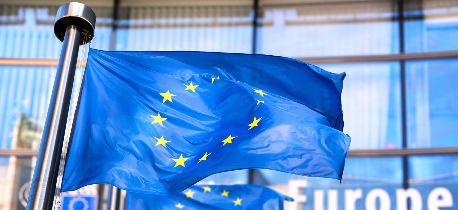 Zu sehen ist eine EU-Flagge vor einem Bürogebäude.